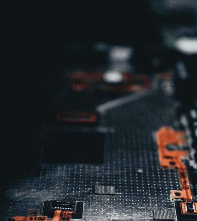 Close-up of a dark circuit board showcasing electronic components and connections.